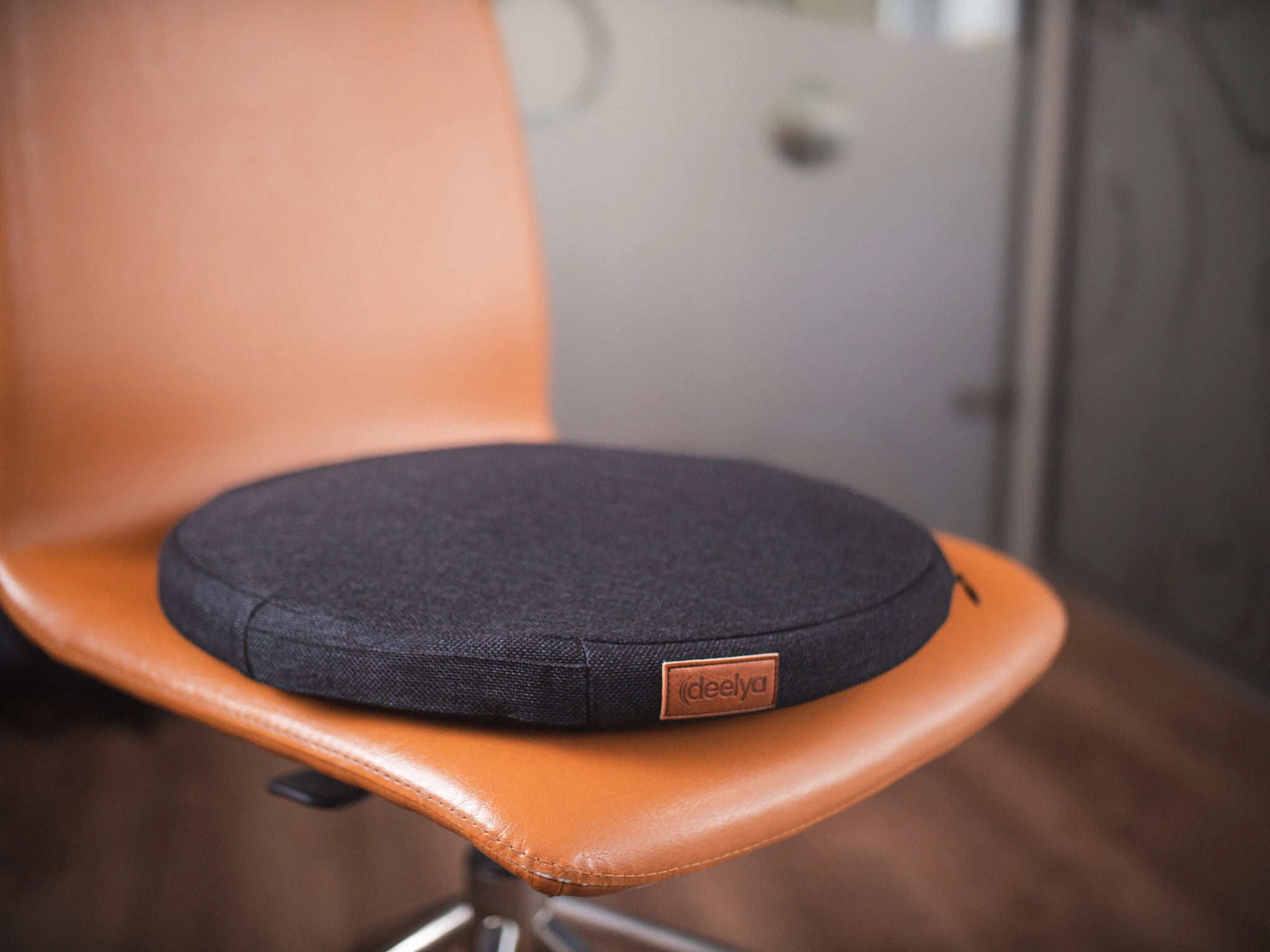 Le support d'assise active DEELYA coloris noir Bora positionné sur une chaise de bureau à roulettes.