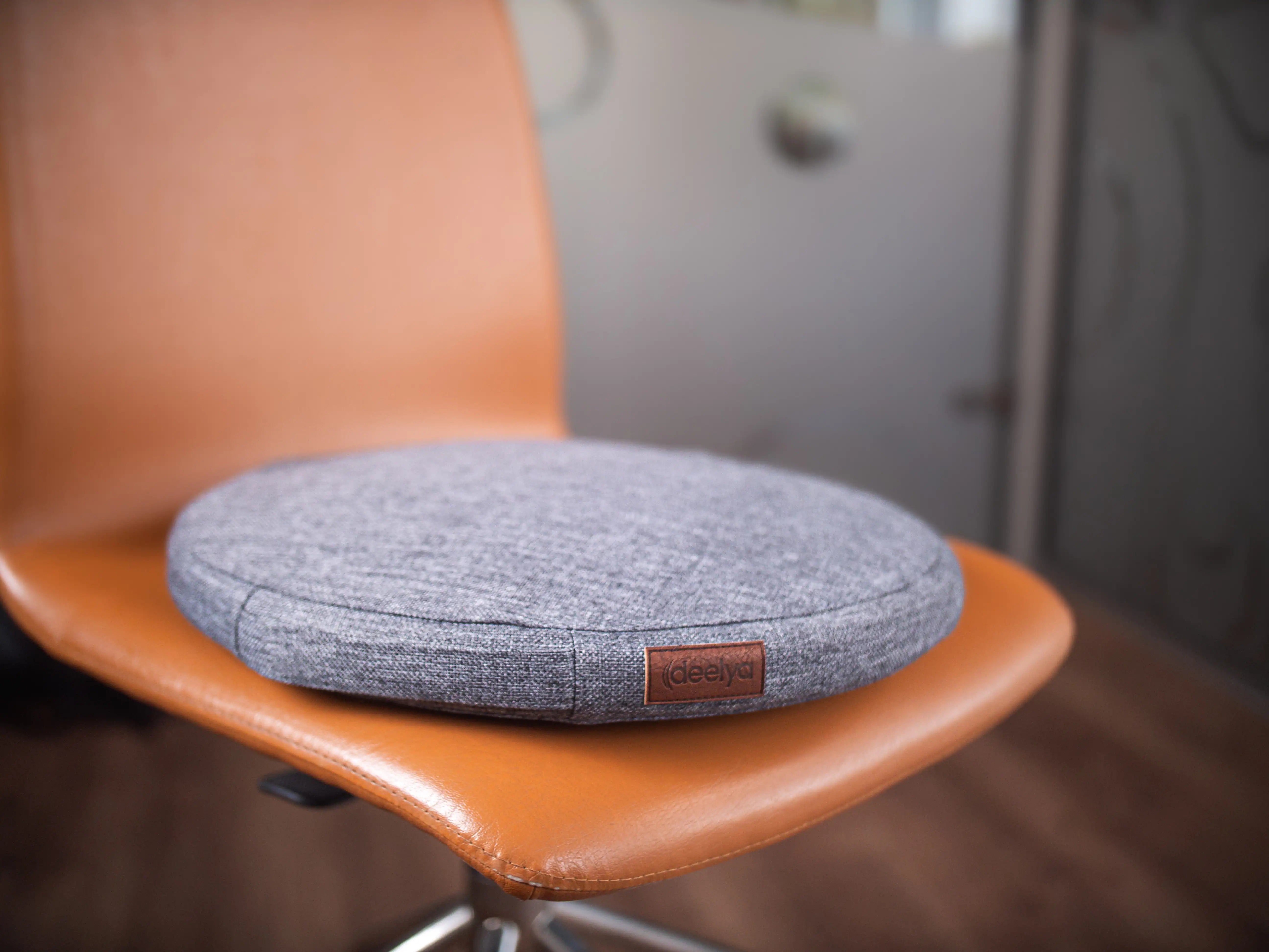 Le support d'assise active DEELYA en tissu chiné gris Seren posé sur une chaise de bureau.