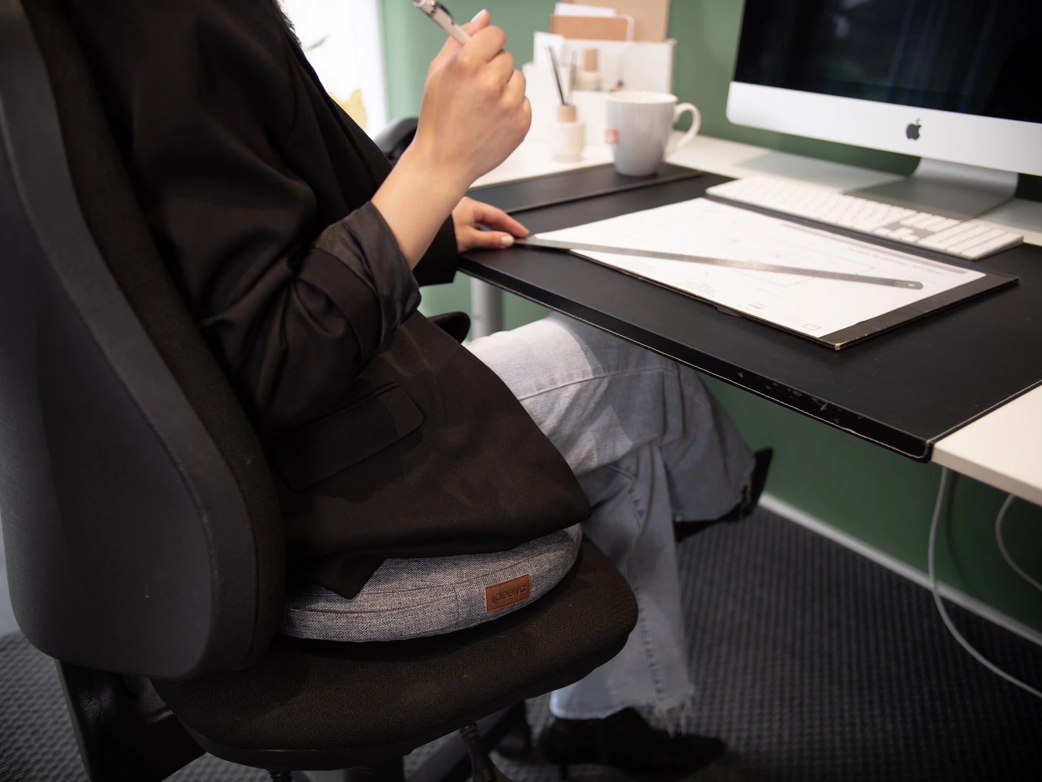 Une collaboratrice est assise sur son support d'assise dynamique DEELYA, installé dans le cadre d'un projet d'aménagement d'espaces flex.